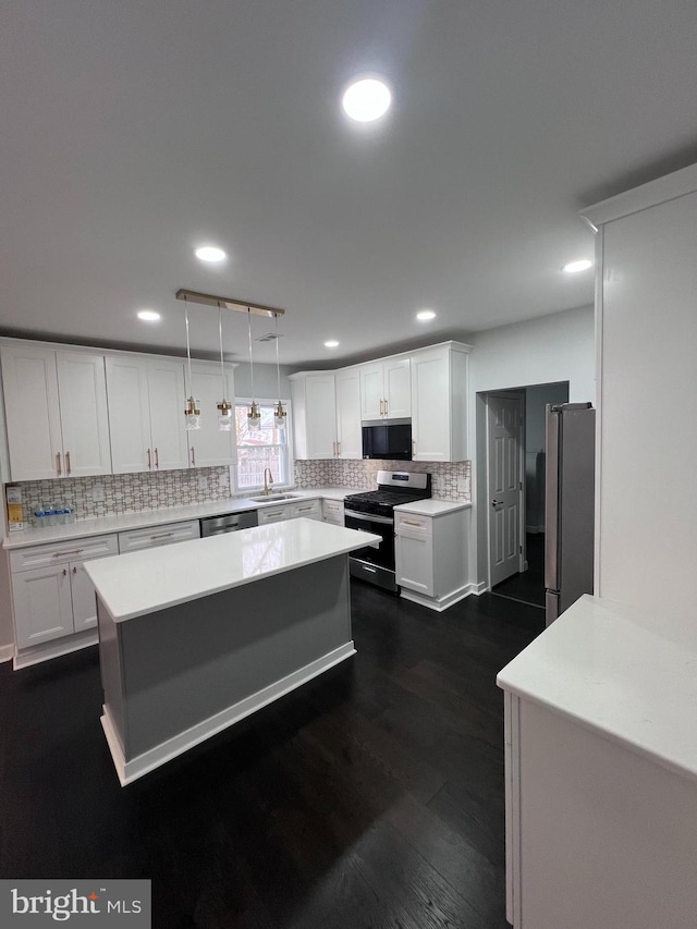 kitchen featuring white cabinets, hanging light fixtures, dark hardwood / wood-style floors, tasteful backsplash, and stainless steel appliances