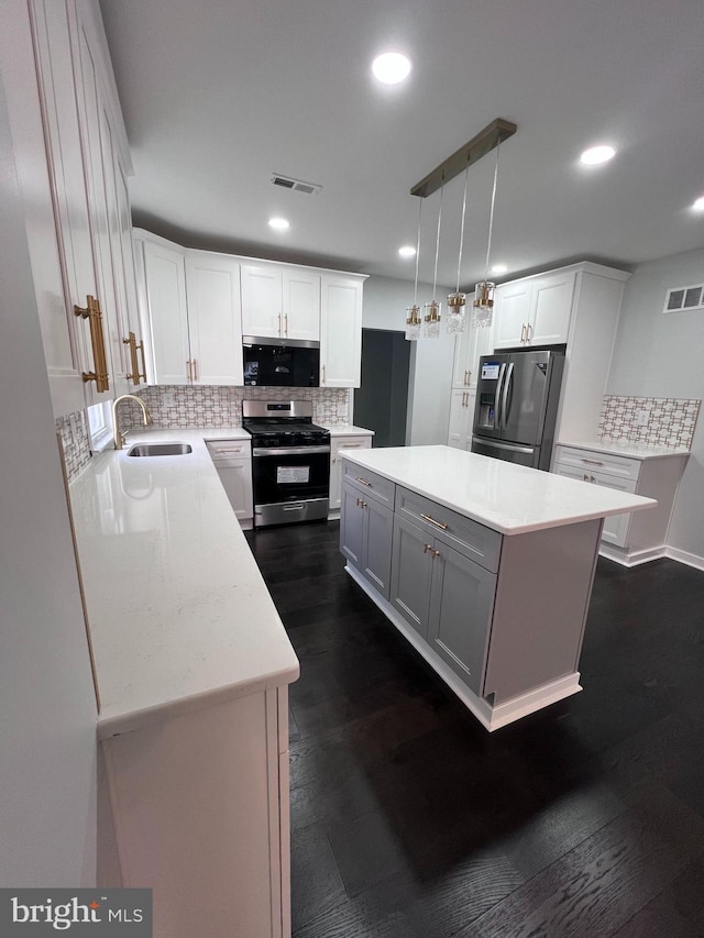 kitchen with stainless steel appliances, dark wood-type flooring, decorative light fixtures, a center island, and white cabinetry