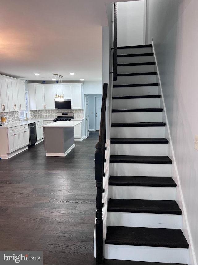 stairway with sink and hardwood / wood-style flooring