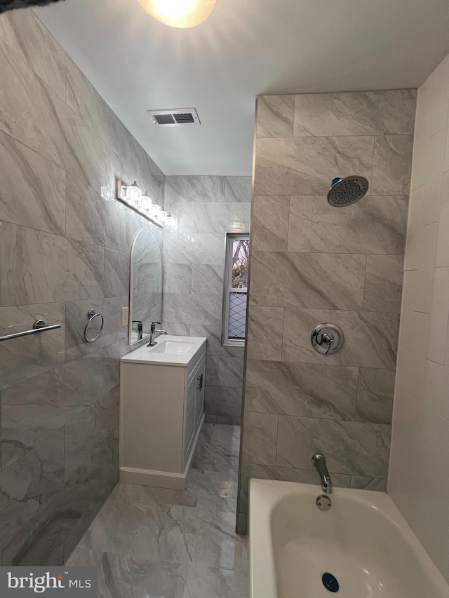 bathroom featuring vanity, tiled shower / bath combo, and tile walls