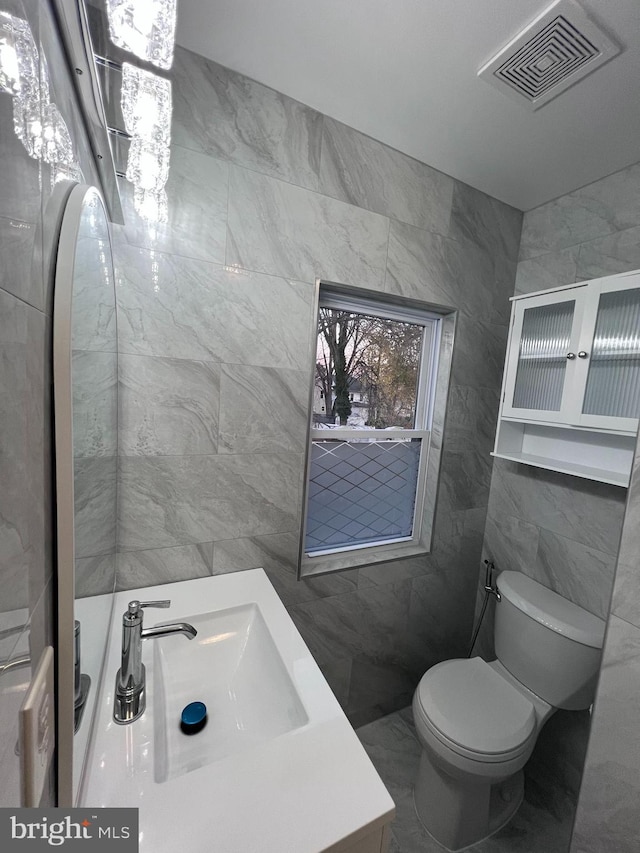 bathroom featuring vanity, toilet, and tile walls