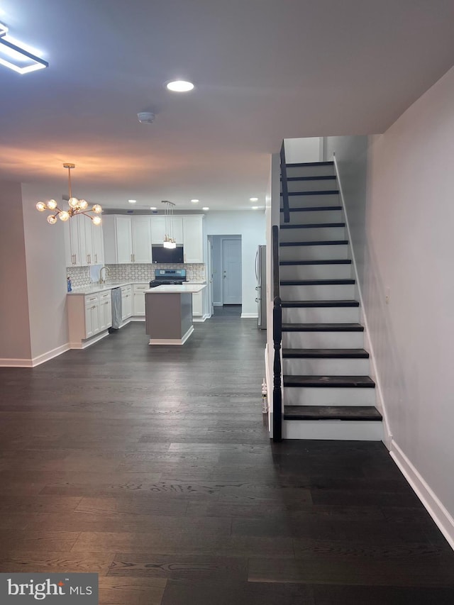 stairs with hardwood / wood-style floors, sink, and an inviting chandelier