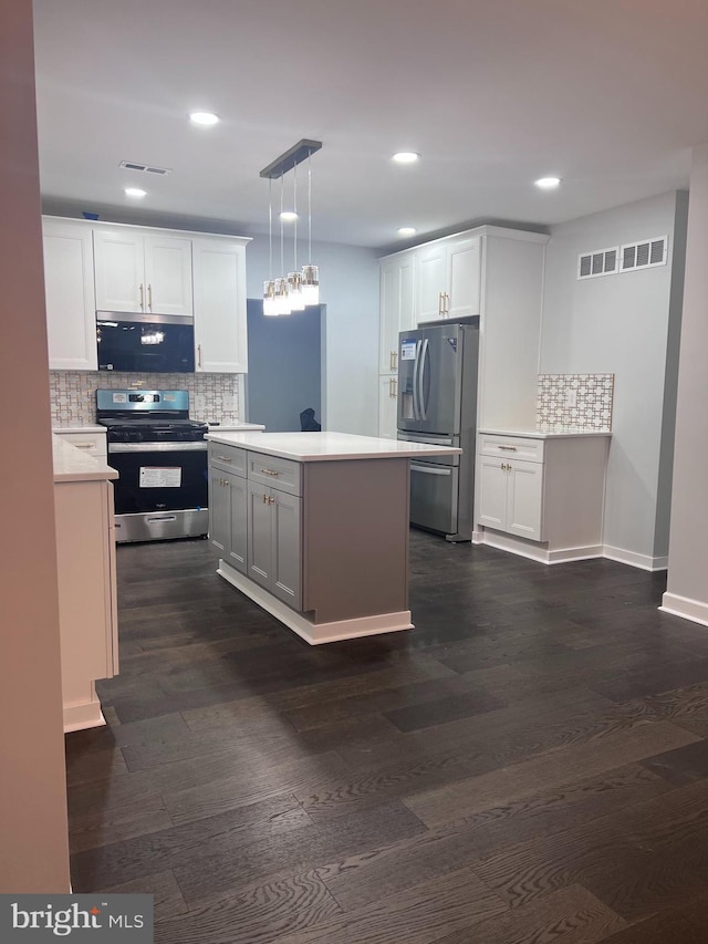 kitchen with white cabinets, pendant lighting, dark hardwood / wood-style floors, and appliances with stainless steel finishes