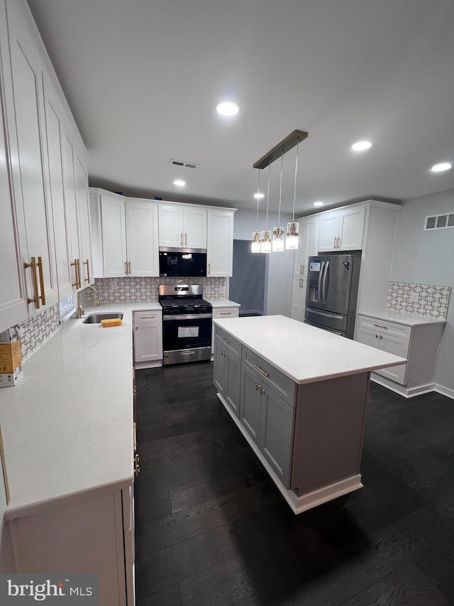 kitchen with stainless steel appliances, white cabinetry, hanging light fixtures, and dark wood-type flooring