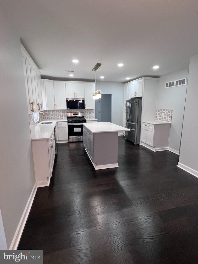 kitchen featuring white cabinetry, dark wood-type flooring, decorative light fixtures, decorative backsplash, and appliances with stainless steel finishes