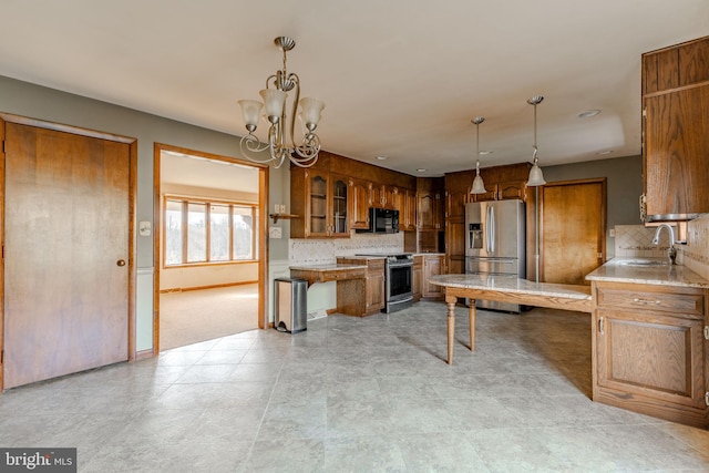 kitchen featuring decorative backsplash, appliances with stainless steel finishes, an inviting chandelier, and sink