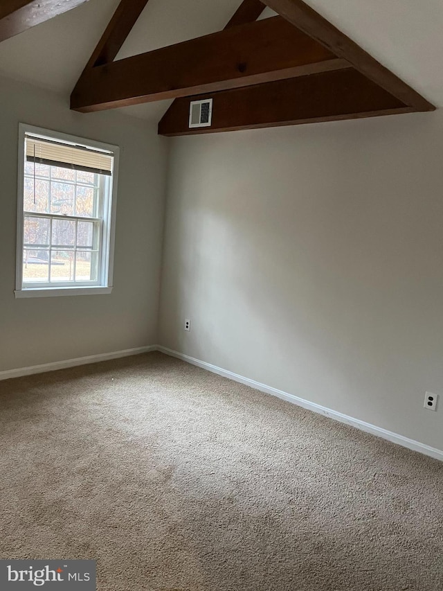 spare room featuring vaulted ceiling with beams and carpet