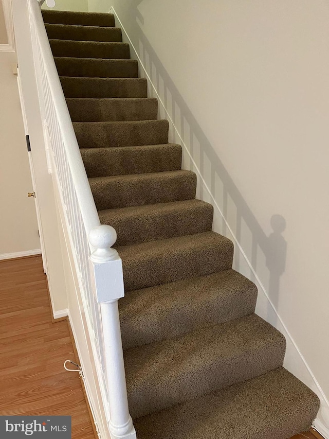 stairway featuring decorative columns and hardwood / wood-style flooring