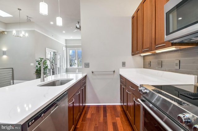 kitchen featuring sink, stainless steel appliances, light stone counters, dark hardwood / wood-style floors, and pendant lighting