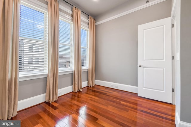 spare room featuring plenty of natural light, dark hardwood / wood-style flooring, and ornamental molding