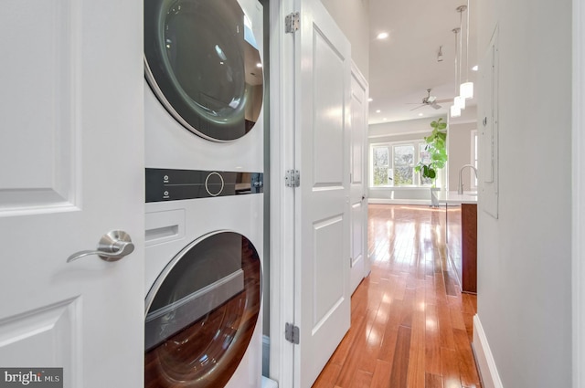 laundry room with ceiling fan, light hardwood / wood-style floors, sink, and stacked washer and dryer