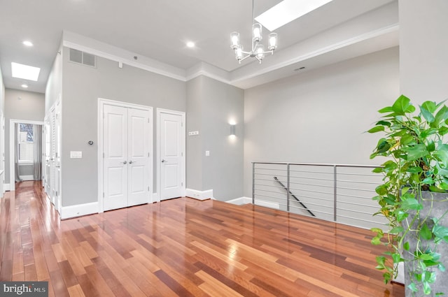 interior space featuring hardwood / wood-style flooring, a skylight, and a chandelier