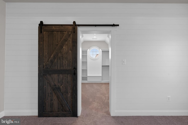 interior space with carpet flooring, a barn door, and vaulted ceiling