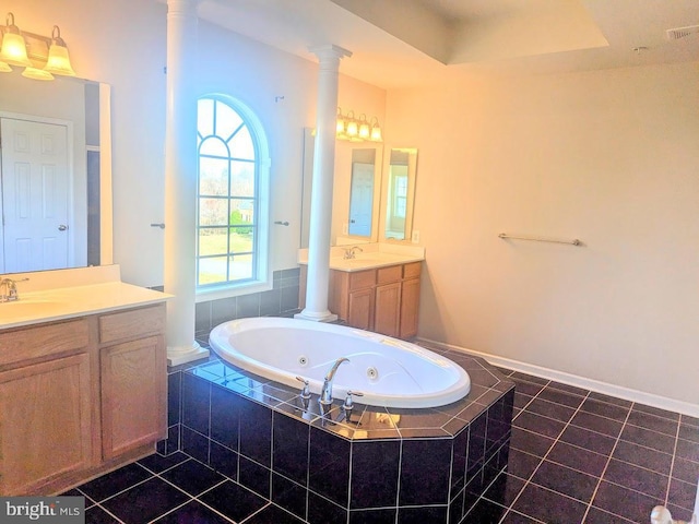 bathroom with tile patterned flooring, vanity, a raised ceiling, and tiled bath