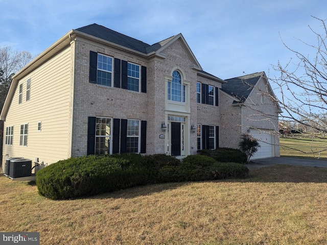 colonial inspired home with central AC unit, a front lawn, and a garage