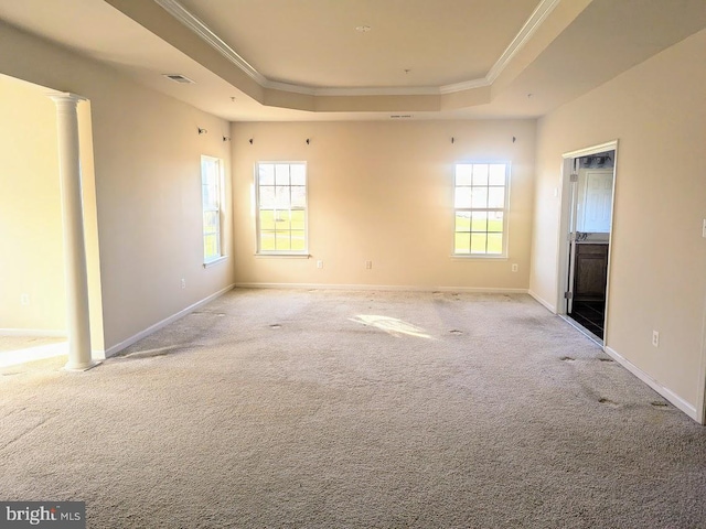 carpeted spare room with a tray ceiling, decorative columns, and crown molding