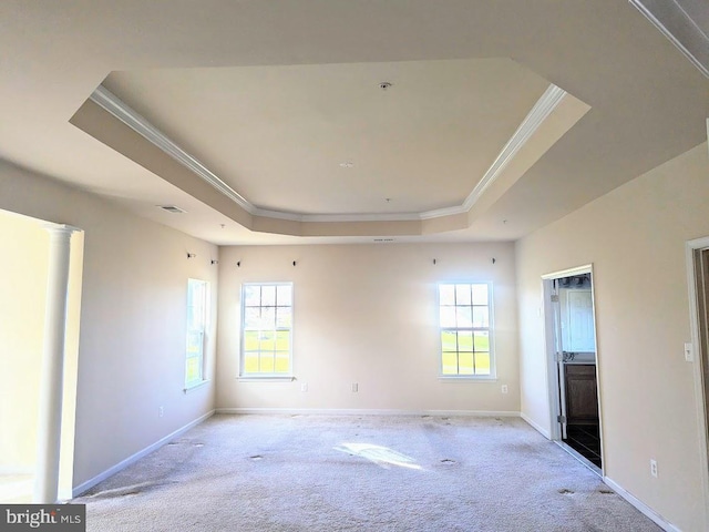 carpeted empty room featuring a raised ceiling, decorative columns, and ornamental molding