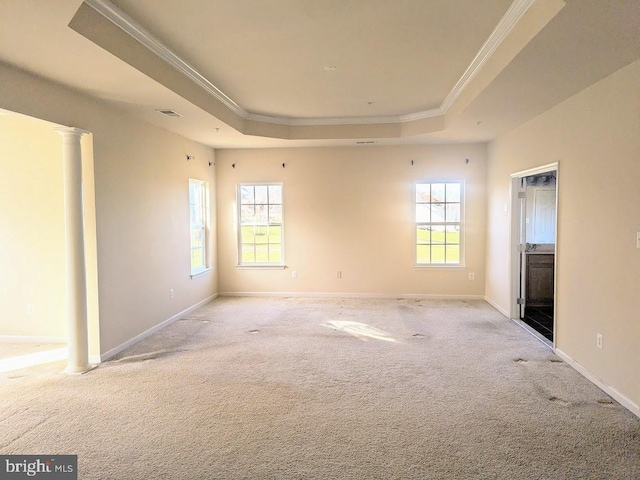 unfurnished bedroom with a tray ceiling, ornate columns, crown molding, and light colored carpet