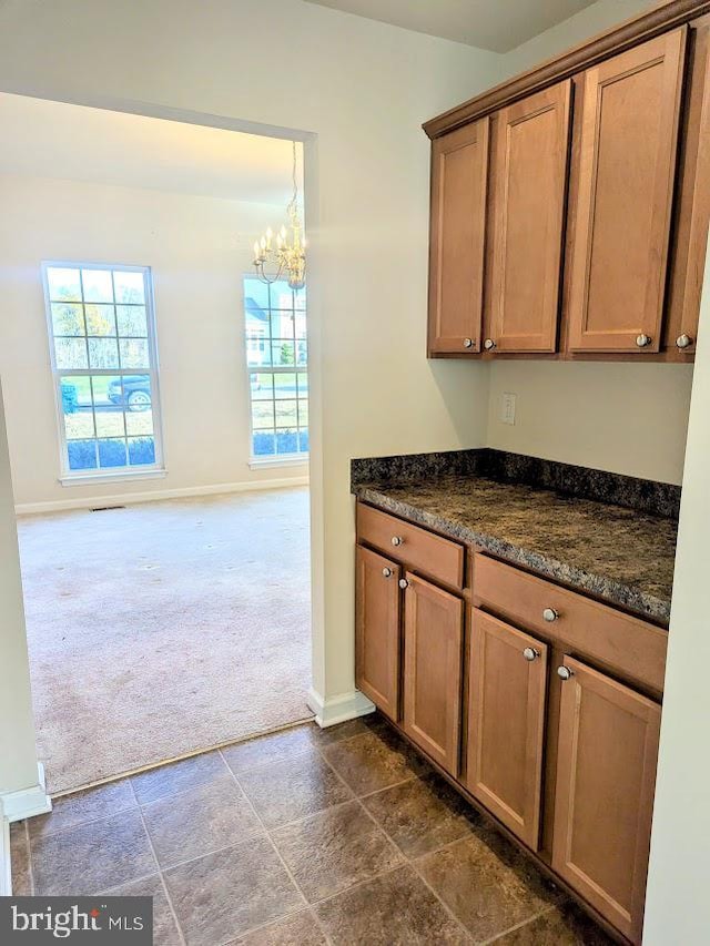 kitchen with dark carpet, a notable chandelier, and dark stone countertops