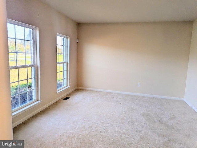 unfurnished room with light colored carpet and a wealth of natural light