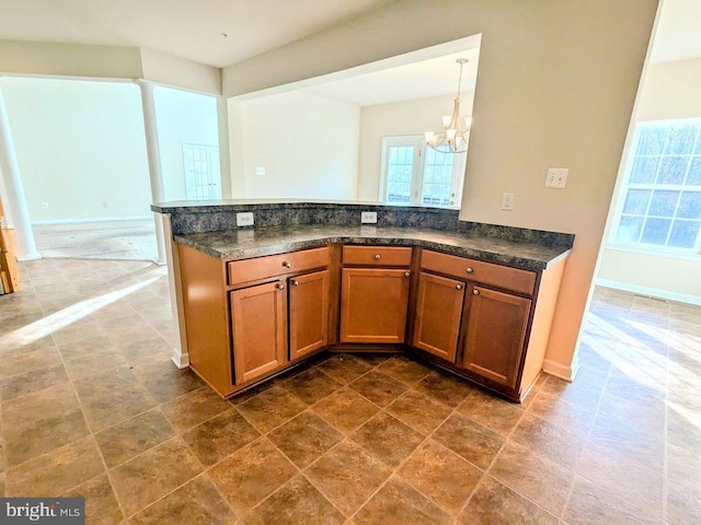 kitchen featuring kitchen peninsula, decorative light fixtures, and an inviting chandelier