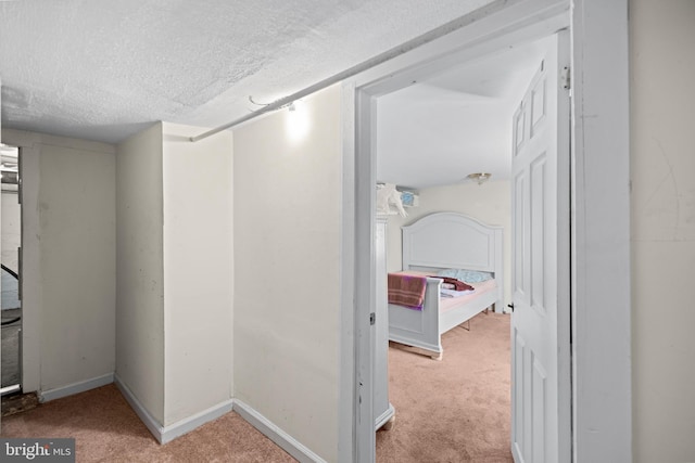 hall with a textured ceiling and light colored carpet