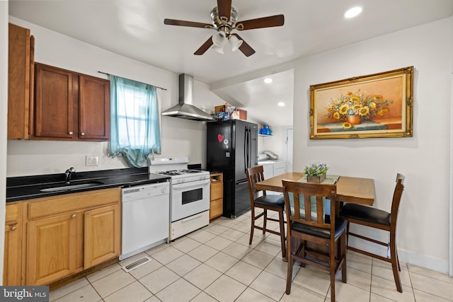 kitchen with white appliances, ceiling fan, sink, wall chimney range hood, and light tile patterned floors