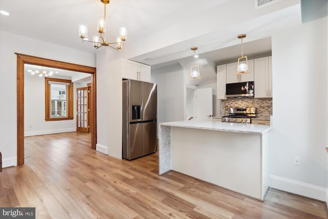 kitchen with light stone countertops, white cabinets, light hardwood / wood-style floors, and appliances with stainless steel finishes