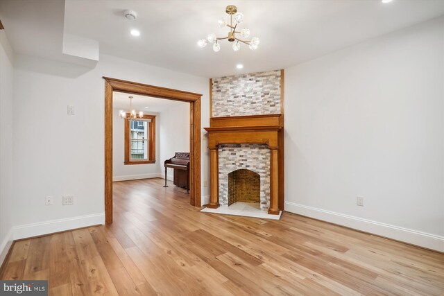 unfurnished living room featuring a chandelier, wood-type flooring, and a fireplace