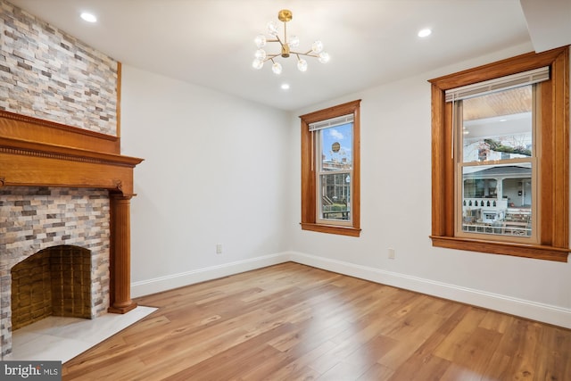 unfurnished living room with a fireplace, light hardwood / wood-style floors, and a notable chandelier