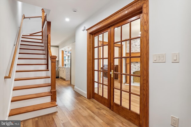 stairs featuring hardwood / wood-style floors and french doors