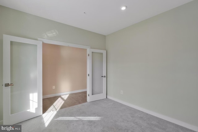 unfurnished bedroom with light colored carpet and french doors