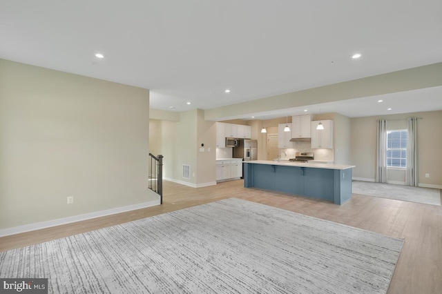 kitchen featuring a center island, white cabinets, hanging light fixtures, light hardwood / wood-style flooring, and stainless steel appliances