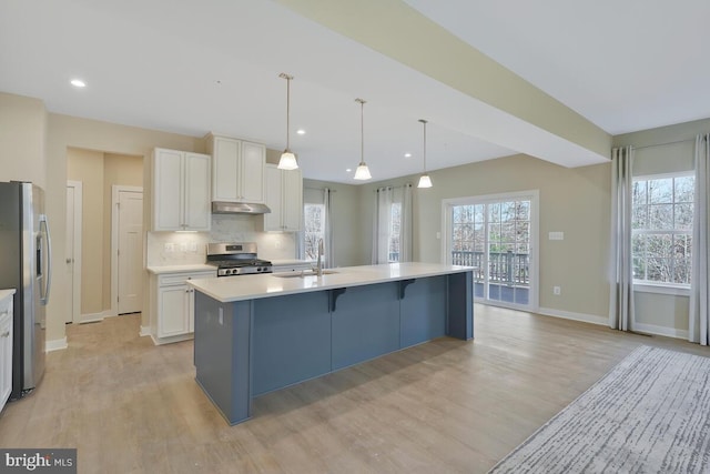 kitchen with appliances with stainless steel finishes, white cabinetry, a kitchen island with sink, and sink