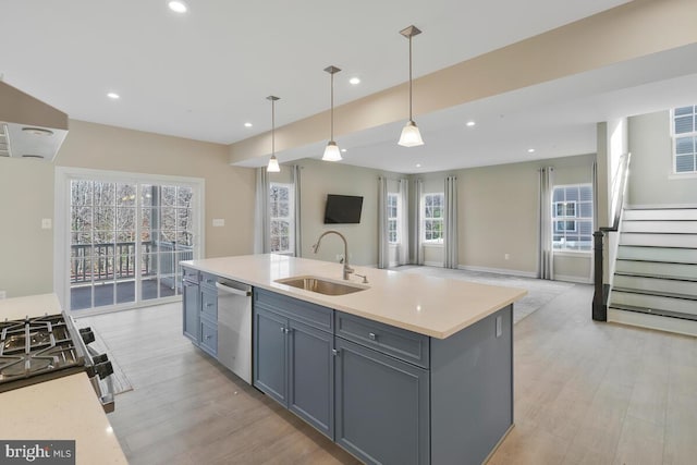 kitchen with a kitchen island with sink, sink, a wealth of natural light, appliances with stainless steel finishes, and decorative light fixtures