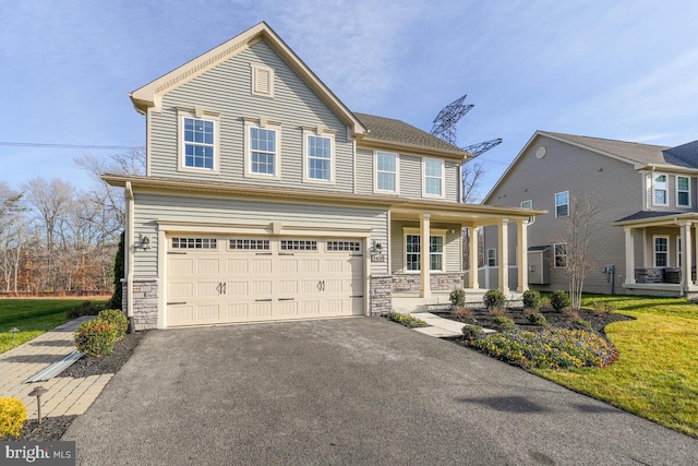 view of front of home featuring a front lawn, covered porch, and a garage