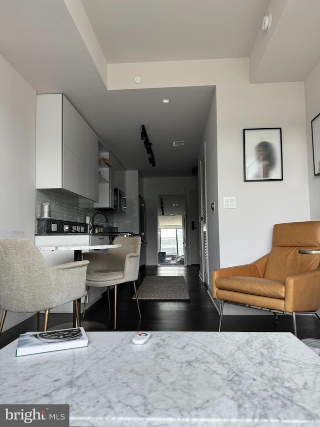 kitchen featuring white cabinets, a kitchen breakfast bar, tasteful backsplash, and hardwood / wood-style floors