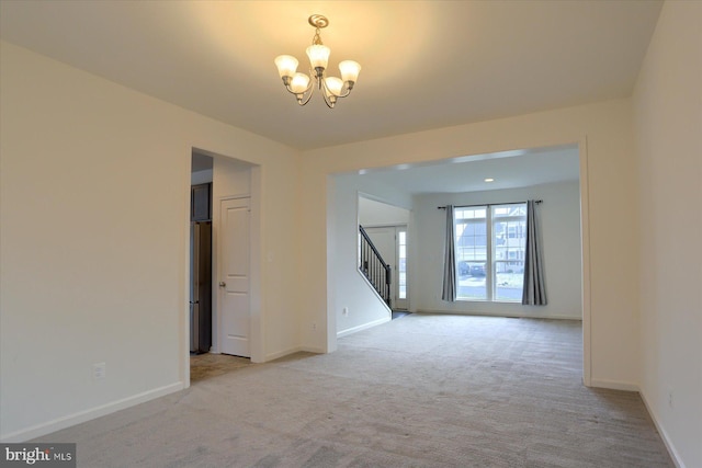 carpeted spare room featuring an inviting chandelier