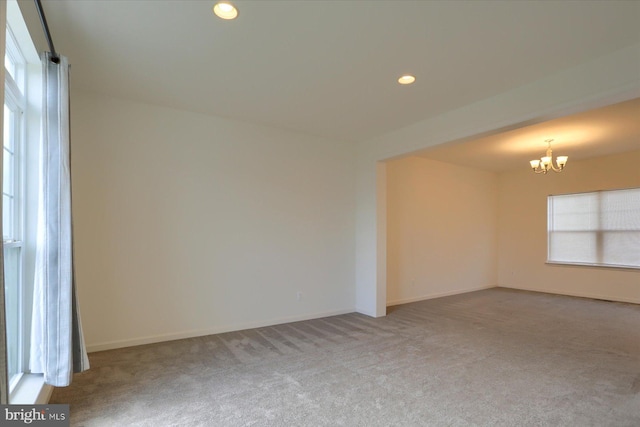 spare room with light colored carpet and a chandelier