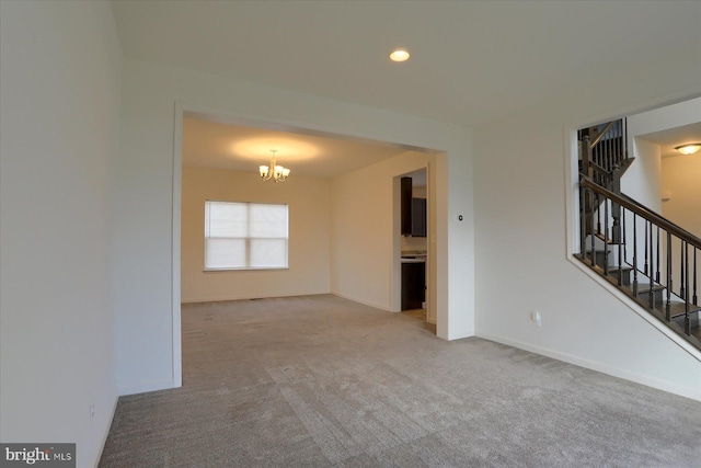 unfurnished living room featuring light carpet and a chandelier