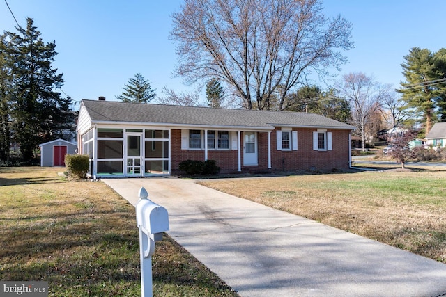 ranch-style house with a sunroom, a storage shed, and a front yard