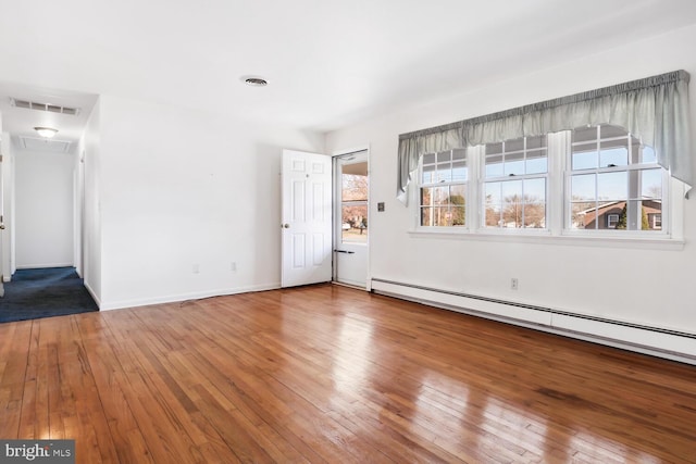 empty room featuring hardwood / wood-style floors and baseboard heating