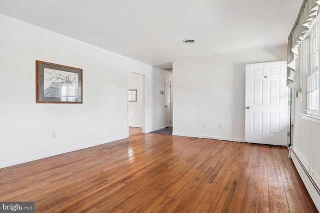 unfurnished room featuring wood-type flooring and a baseboard heating unit