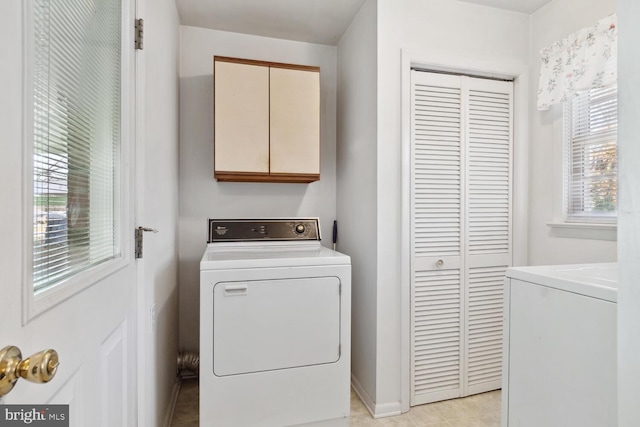 clothes washing area featuring cabinets, washer / dryer, and light tile patterned floors