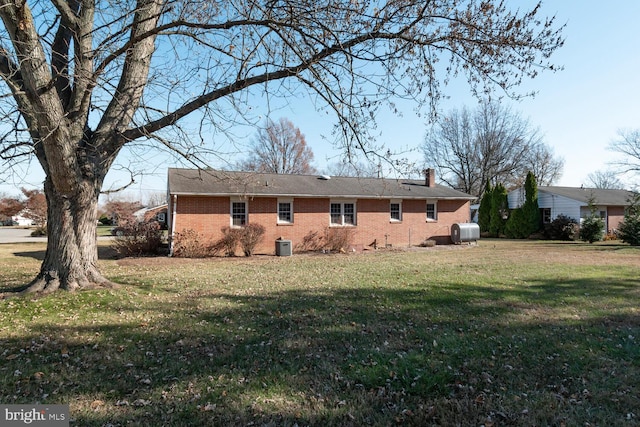 rear view of house with a lawn and cooling unit