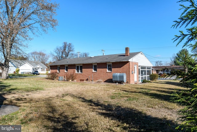 back of property with a lawn and a sunroom