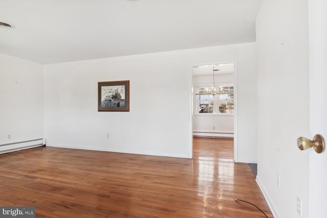 unfurnished room featuring hardwood / wood-style flooring, an inviting chandelier, and baseboard heating