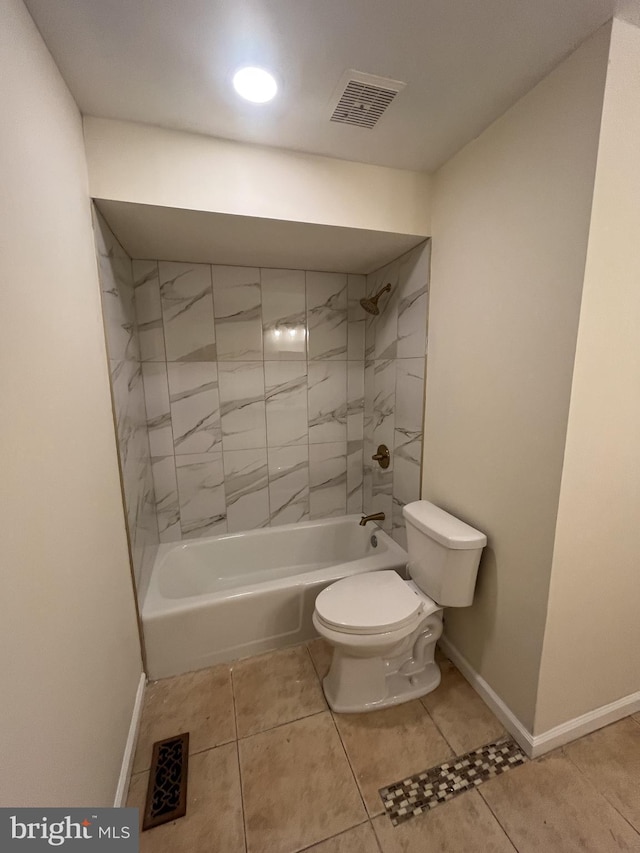 bathroom featuring tile patterned flooring, tiled shower / bath combo, and toilet