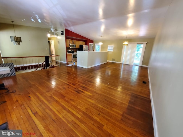 unfurnished living room featuring wood-type flooring, ceiling fan with notable chandelier, and vaulted ceiling