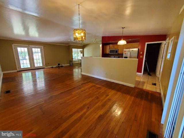 unfurnished living room with ceiling fan with notable chandelier, french doors, and dark hardwood / wood-style flooring